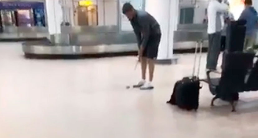 Man Practices Putting at Airport Baggage Claim