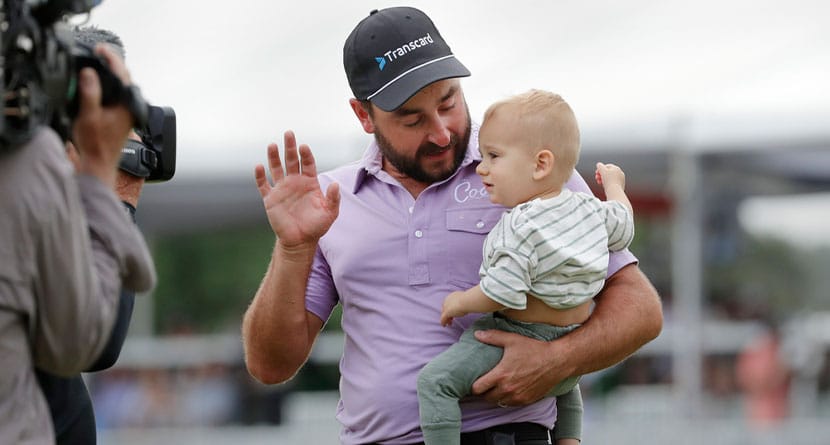 Stephan Jaeger holds son Fritz while trying to get him to wave to TV cameras after his victory in the Houston Open golf tournament Sunday, March 31, 2024, in Houston. (AP Photo/Michael Wyke)