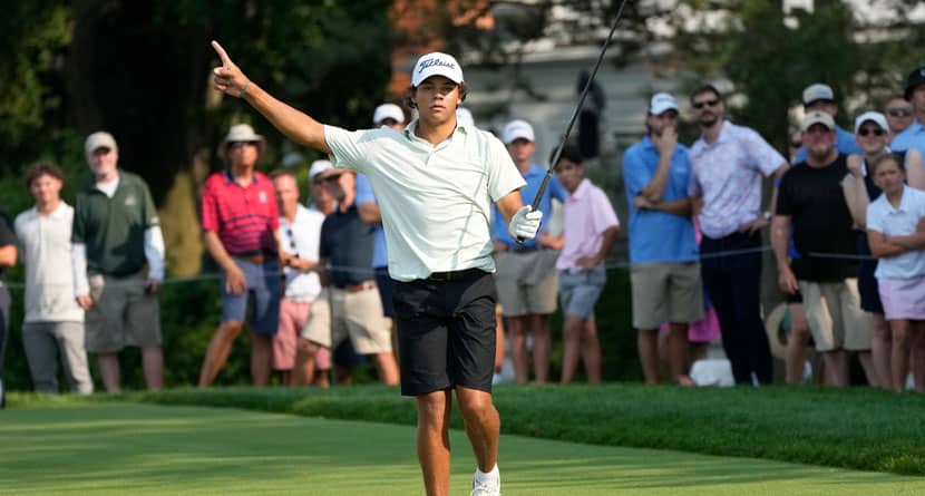 Charlie Woods signals after hitting off the 18th tee during the second round of stroke play of the U.S. Junior Amateur Golf Championship, Tuesday, July 23, 2024, in Bloomfield Township, Mich. (AP Photo/Carlos Osorio)