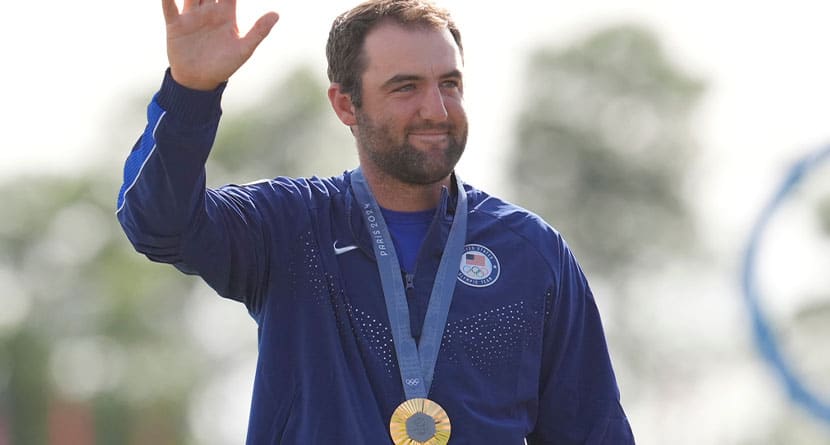 Scottie Scheffler, of the United States, waves to the crowd with his gold medal for men's golf during the medal ceremony at the 2024 Summer Olympics, Sunday, Aug. 4, 2024, at Le Golf National in Saint-Quentin-en-Yvelines, France. Scottie Scheffler, of the United States, won the gold medal with Tommy Fleetwood, of Britain, silver and Hideki Matsuyama, of Japan, the bronze.(AP Photo/Matt York)