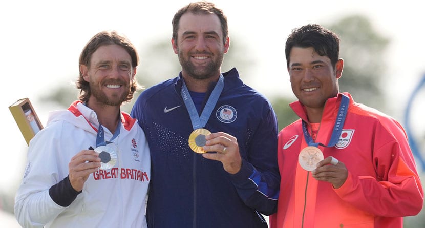 Gold medalist Scottie Scheffler, of the United States, centre, with Tommy Fleetwood, of Britain, silver medal, and Hideki Matsuyama, of Japan, with the bronze medal pose for the media following the medal ceremony for men's golf at the 2024 Summer Olympics, Sunday, Aug. 4, 2024, at Le Golf National in Saint-Quentin-en-Yvelines, France. (AP Photo/George Walker IV)