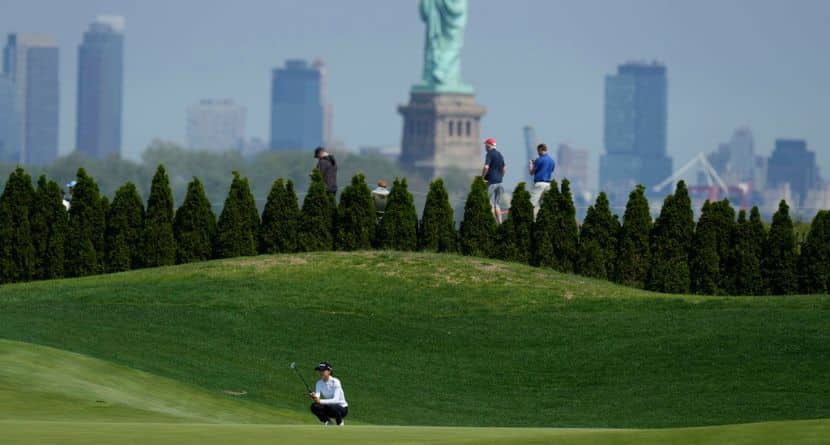 Lydia Ko, of New Zealand, bottom, lines a putt on the 13th green as the Statue of Liberty looms in the distance during the first round of the Mizuho Americas Open LPGA golf tournament, Thursday, May 8, 2025, in Jersey City, N.J. (AP Photo/Seth Wenig)
