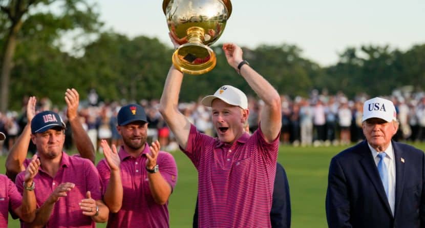 President Donald Trump, right, watches as USA team captain Brandt Snedeker holds the Presidents Cup trophy after the Presidents Cup golf tournament against the International team at Medinah Country Club, Sunday, Sept. 27, 2026, in Medinah, Ill. (AP Photo/Chris Carlson)